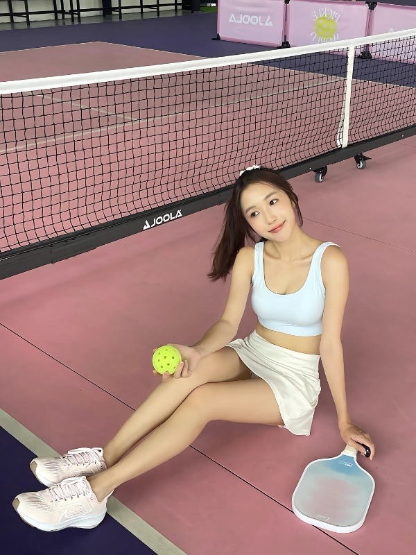 Ảnh gái chơi pickle ball ngồi bên bóng vàng