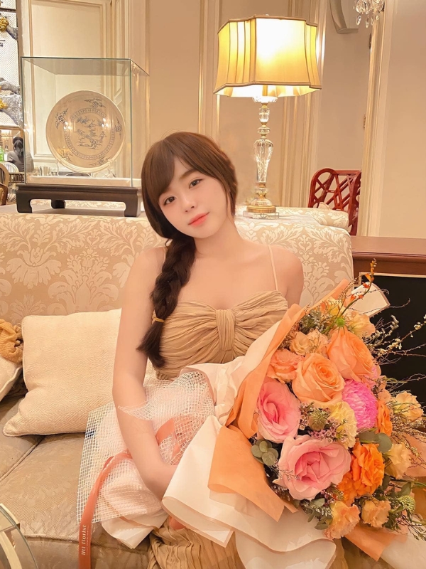 Thần thái sang trọng, cầm bó hoa rực rỡ.